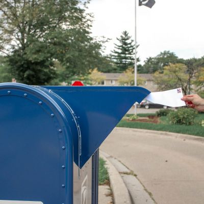 crop-person-putting-envelope-in-mailbox-on-street-1550335